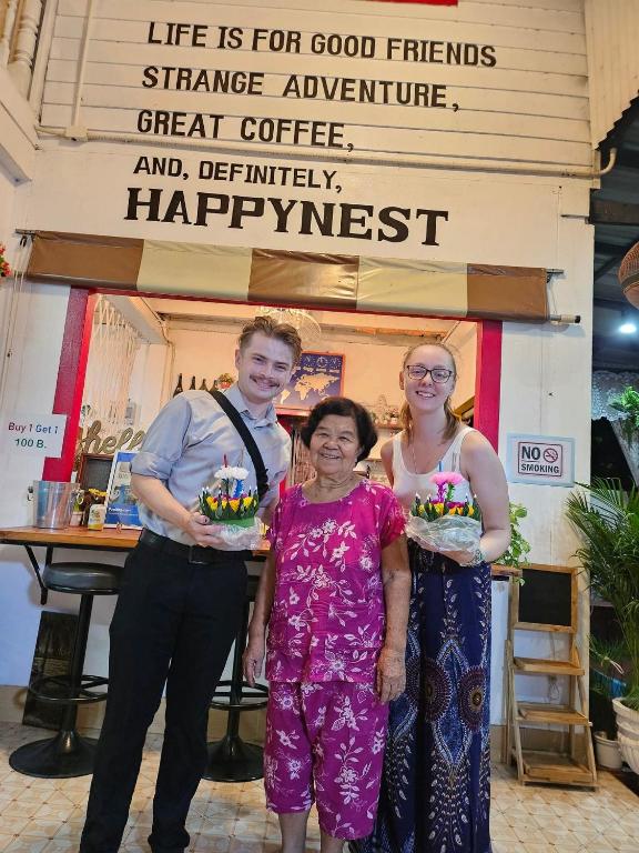 three people standing in front of a store holding cakes at Baan Mae Somkid Homestay in Sukhothai