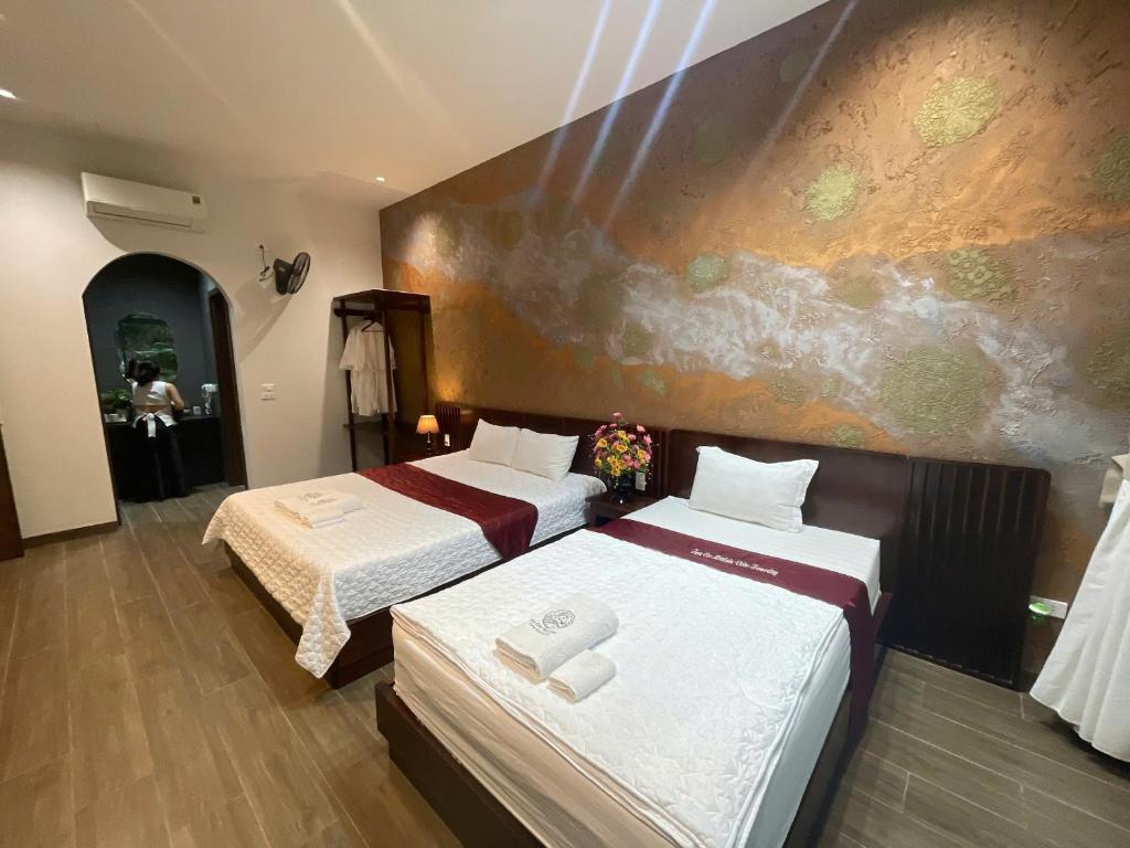 a bedroom with two beds and a painting on the wall at Mountainview tam coc villa in Vũ Lâm