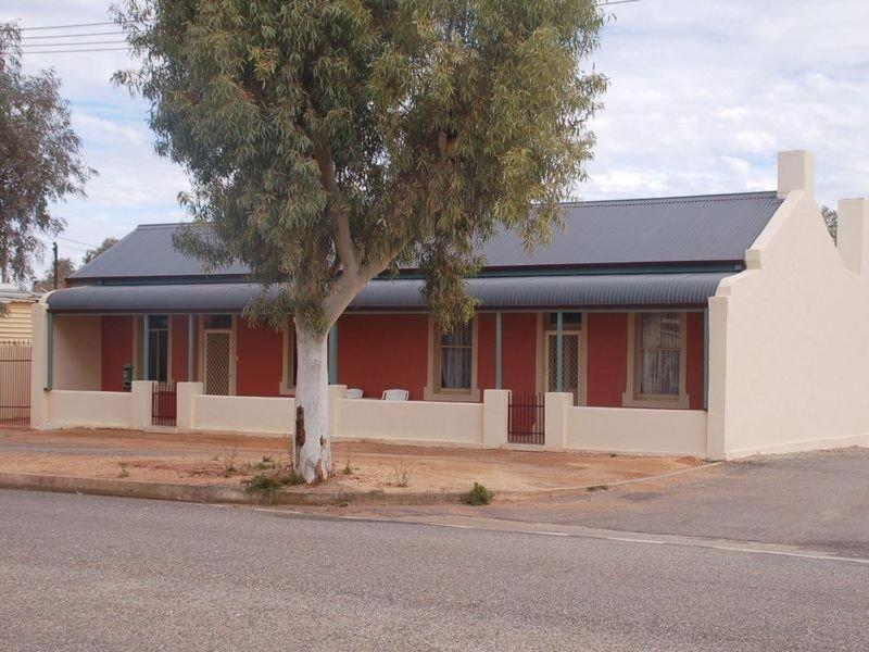 a red and white building with a tree in front of it at Jadan Cottages in Broken Hill