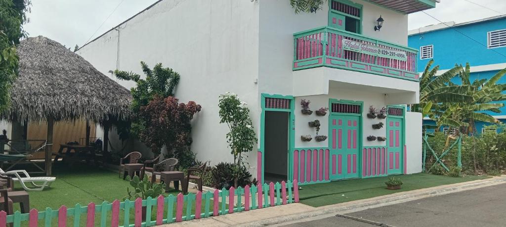 a white building with a pink and green door at Hostal Johnnier Macao Punta Cana in Punta Cana