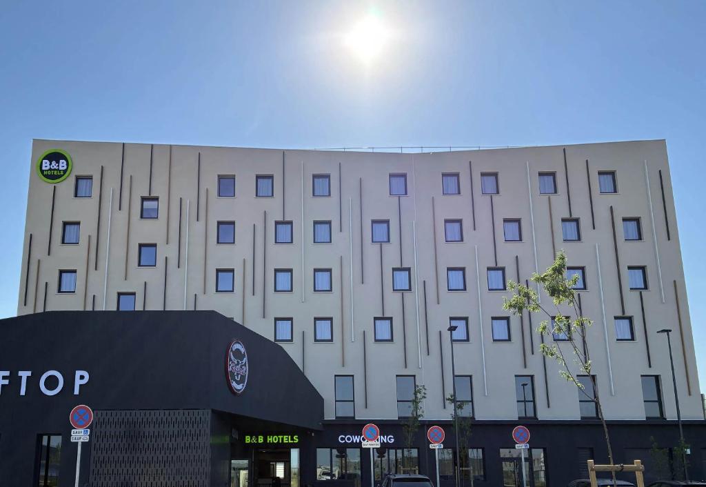 a large white building with a sign in front of it at B&B HOTEL Cap d'Agde Bessan in Bessan