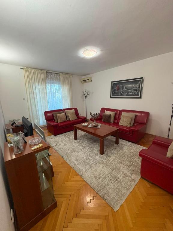 a living room with red couches and a coffee table at Apartman Damir in Čeluga