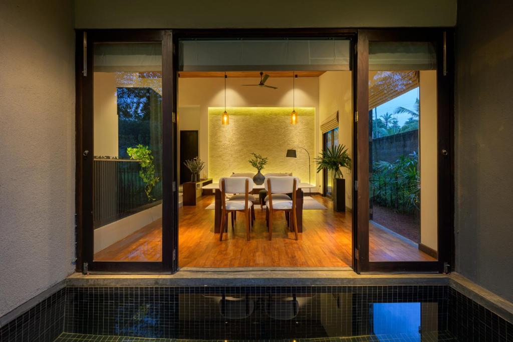 a dining room with glass doors and a table and chairs at The Plunge by Duo Escapes in Gonahena