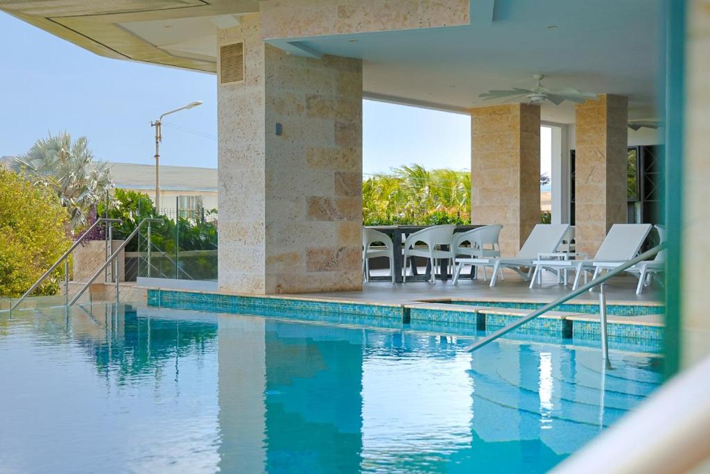 a swimming pool with tables and chairs next to a house at 2 BR Oceanview Condo Coral Shell 3e in Oranjestad