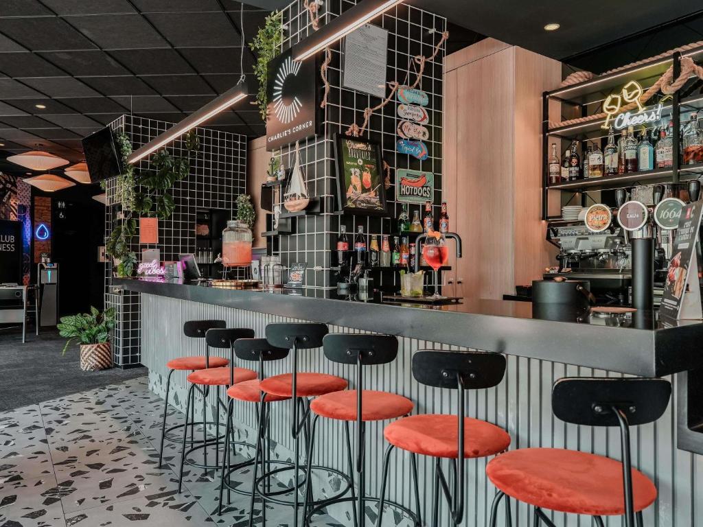 a bar with black and orange stools at ibis Martigues Centre in Martigues