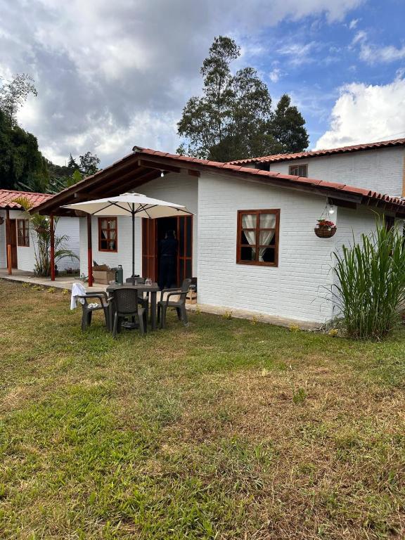a white house with a table and chairs in the yard at Villa Belén in Guarne