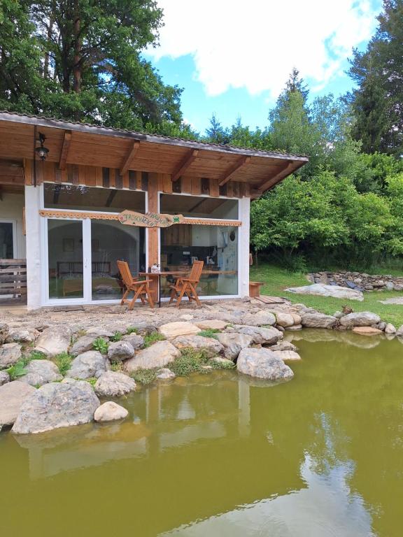 a house with a table and chairs next to a pond at Froschteichhäuschen - Natur und Wellness in Spitzwiesen