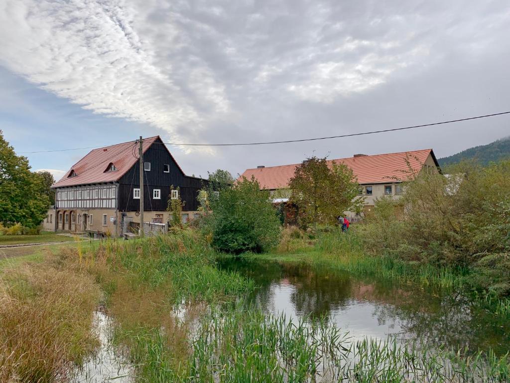 a large building next to a river with buildings at Ferienhof Saalendorf in Großschönau