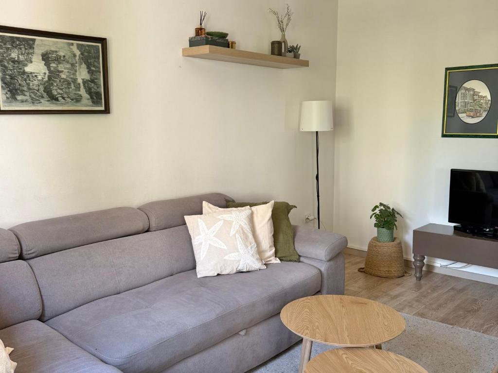 a living room with a gray couch and a table at Guest house Kamelija in Budva