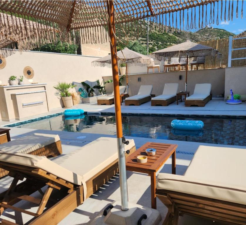 an outdoor pool with lounge chairs and an umbrella at Anestis Studios in Lidia
