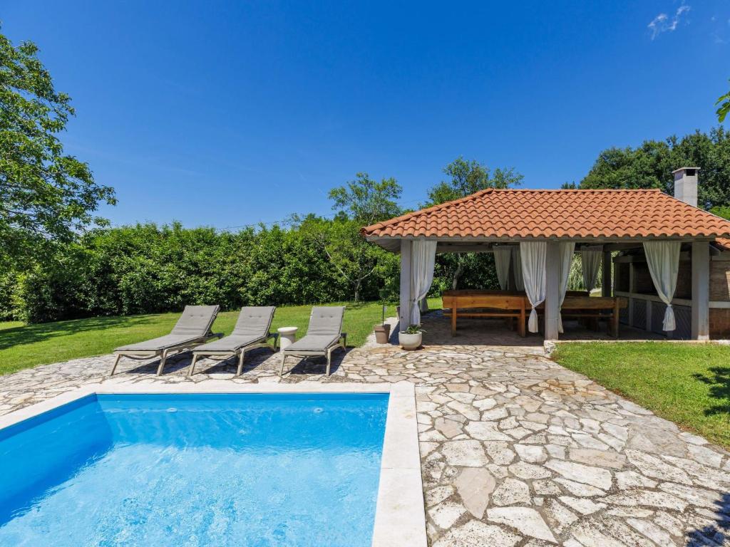 a swimming pool with chairs and a gazebo at Villa Elli by Interhome in Tinjan