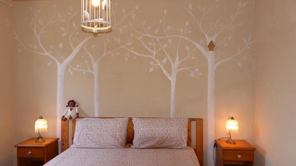 ein Schlafzimmer mit einem Bett mit an der Wand gemalten Bäumen in der Unterkunft Agriturismo Al Respiro Nel Bosco in Camporotondo di Fiastrone