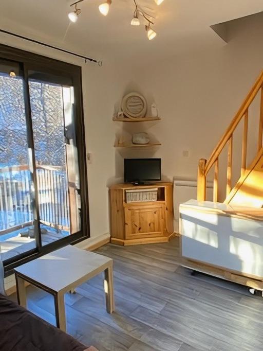 a living room with a television and a balcony at Location duplex ,Station du Seignus d'Allos in Allos