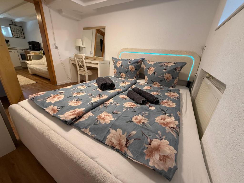 a bed with a blue comforter with pink flowers on it at LaSa Apartment 2 in Villingen-Schwenningen