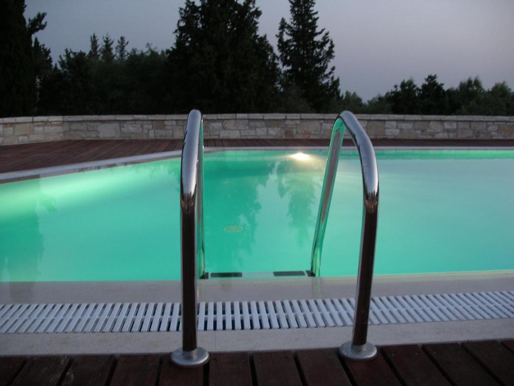 a swimming pool with two empty chairs next to it at Alkyon Villas in Syvota