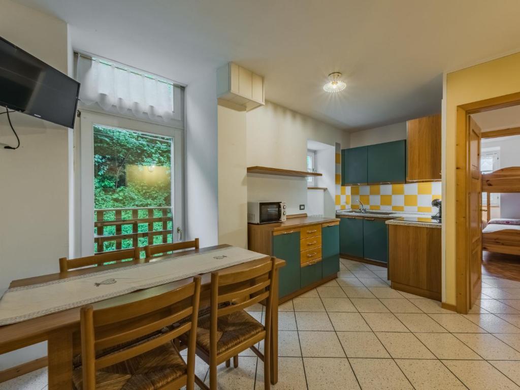 a kitchen with green cabinets and a table with chairs at Apartment Abete by Interhome in Rabbi