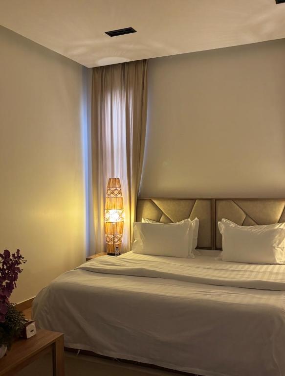 a bedroom with a large white bed with a lamp at شقق لولو in Hail