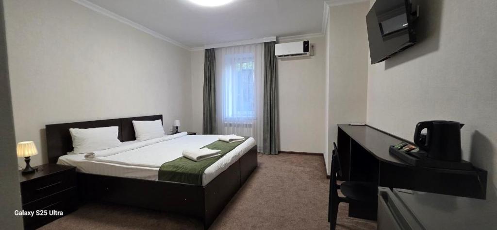a bedroom with a bed and a desk and a television at Archa hotel in Osh