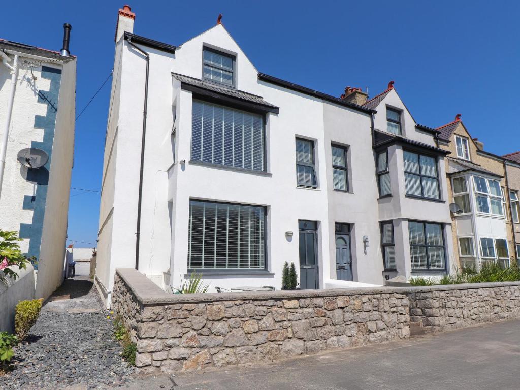 a white house with a stone wall at Ty Haul in Rhosneigr