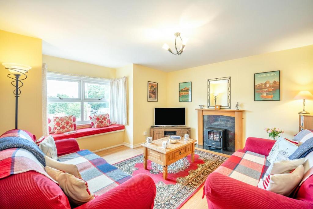 a living room with two red couches and a tv at 2 Bed in Bamburgh oc-nb282 in Bamburgh
