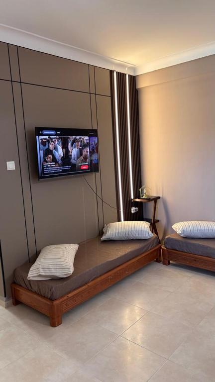 two beds in a room with a tv on the wall at Studio Prestige - 10min de ParkMall in Sétif