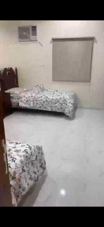 two beds in a white room with floral sheets at المربع سويت in Al Qarhāʼ