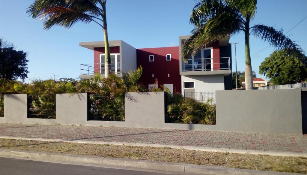 a house on the side of a street with palm trees at Yolo Apartment in Willemstad