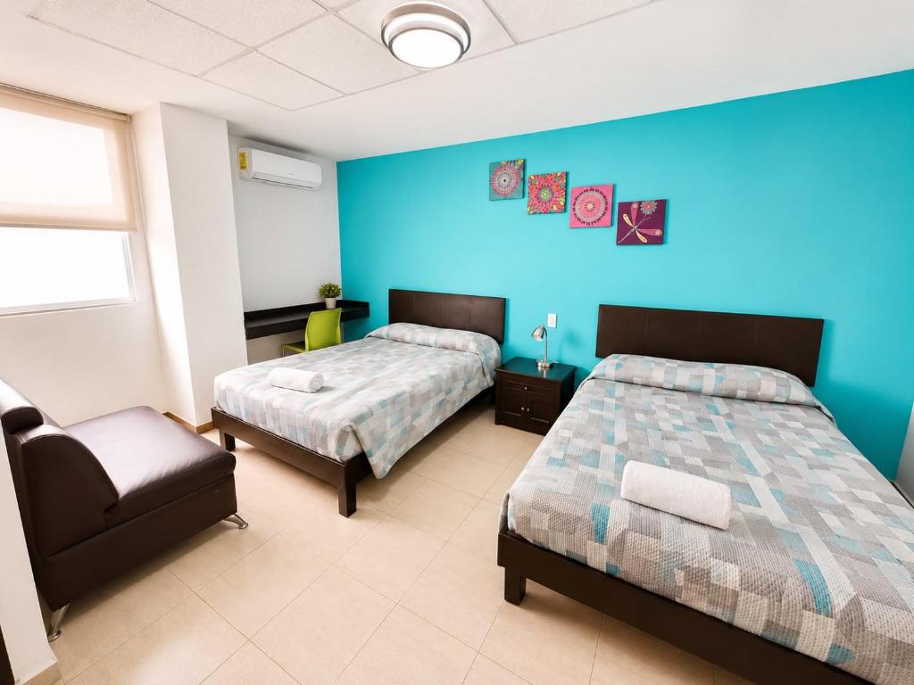 una camera da letto con due letti e una parete blu di Hotel Plazha Express a Tuxtla Gutiérrez