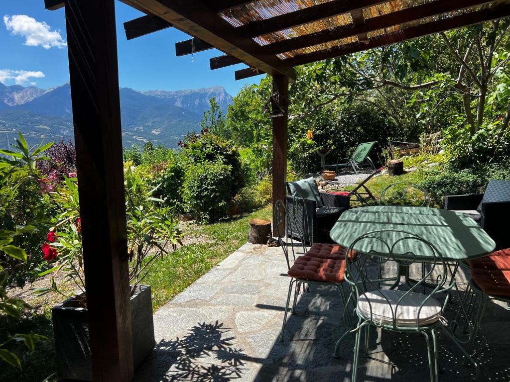 a table and chairs on a patio with a view at MAISON DES VIGNES in Embrun