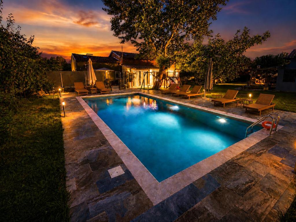 a swimming pool in a backyard at dusk at Pegasus Pool Villas Kavala in Kavála