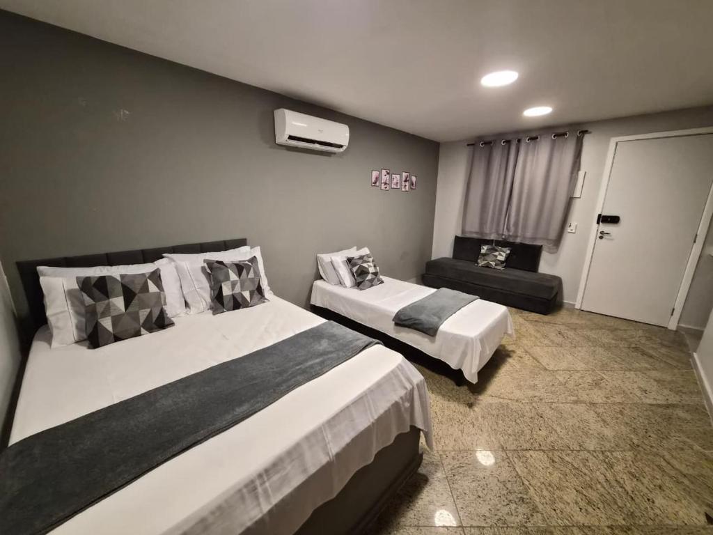 a hotel room with two beds and a couch at CaisSuites in Cabo Frio
