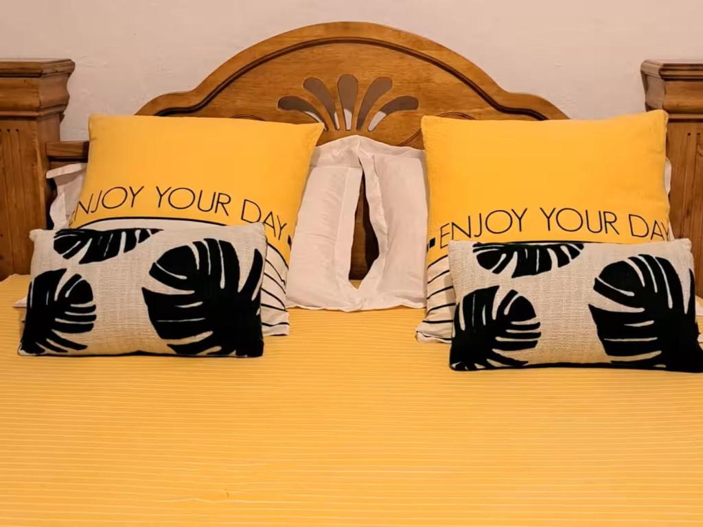 a bed with yellow and white pillows on it at Case Kiyas in Mamoudzou