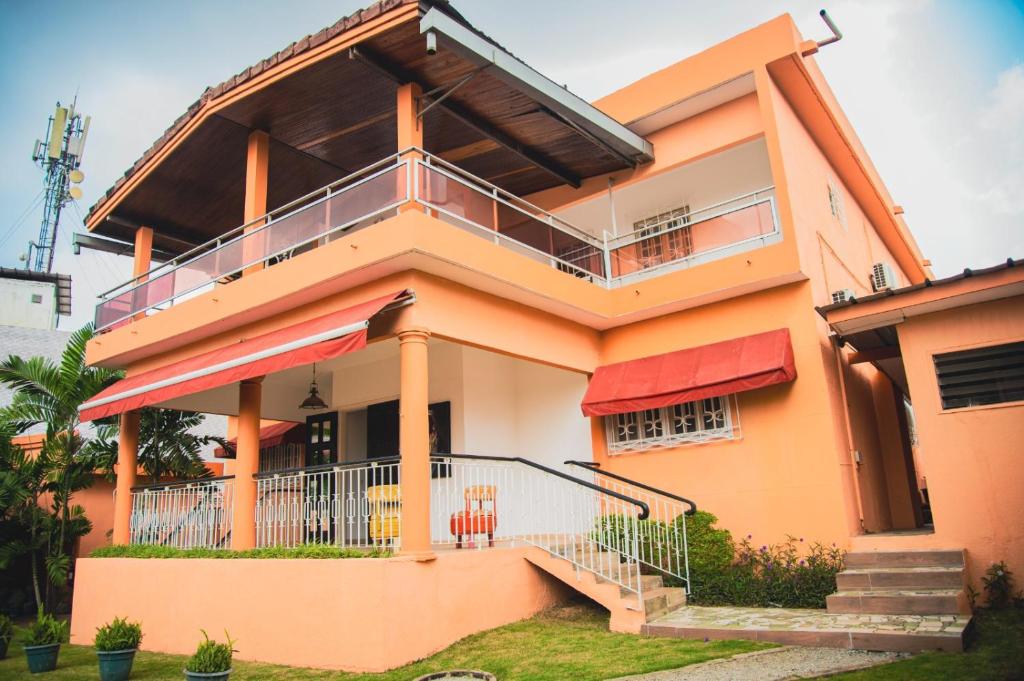a orange house with a balcony and stairs at Résidence Touraco in Abidjan