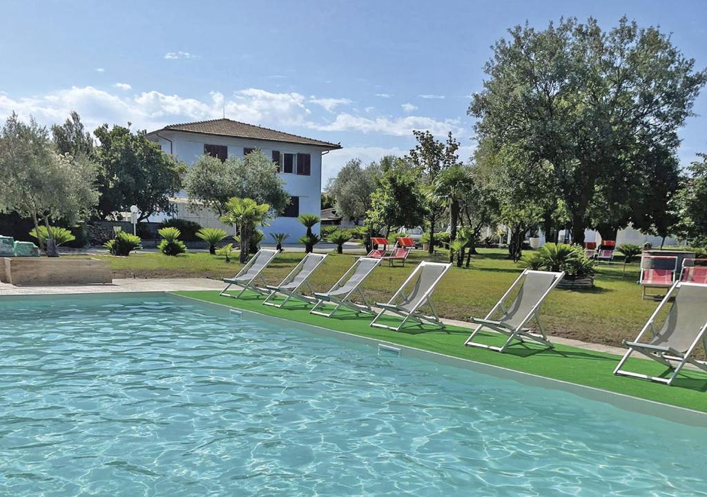 a group of lawn chairs sitting next to a pool at Residence Il Pavone in Marina di Campo