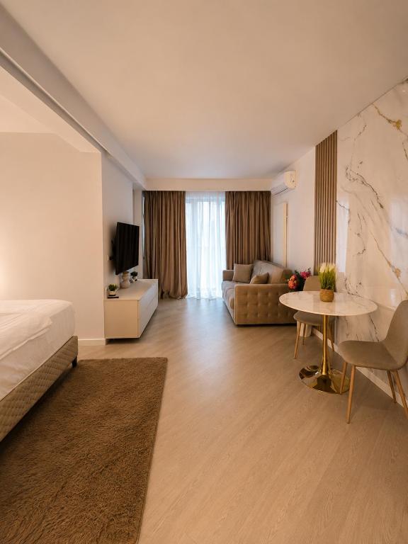 a hotel room with a bed and a couch and a table at Cortina North Luxury Studio in Voluntari