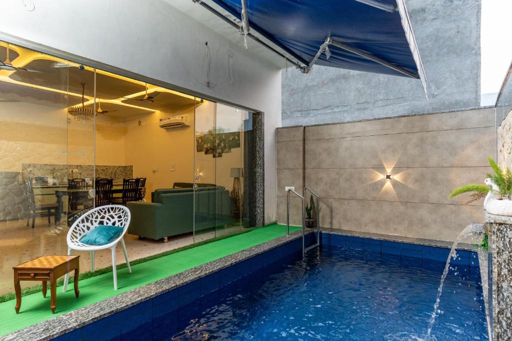 a pool with a table and a chair next to a house at Velmora Stay Premium Luxury Villa with Private Pool in Amritsar