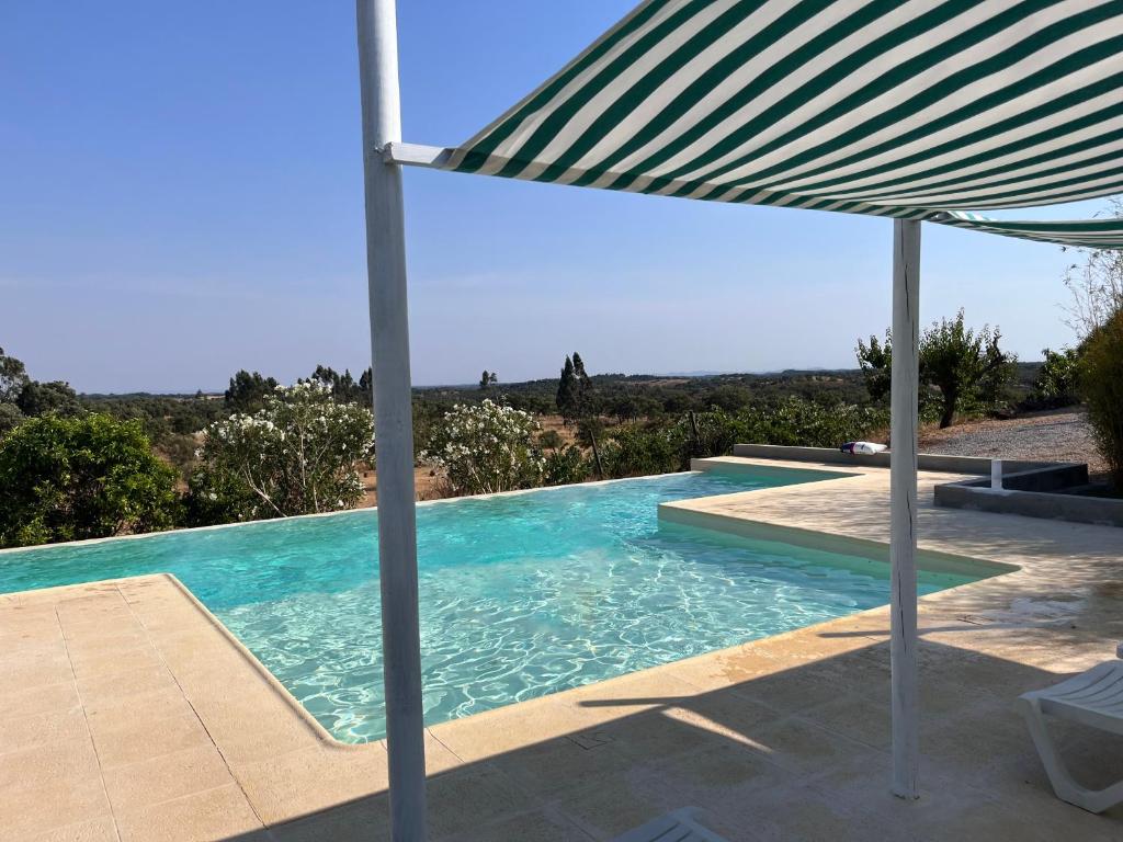 a swimming pool with an umbrella next to a table at Monte da Casa Branca by Hi Alentejo in São Bartolomeu da Serra