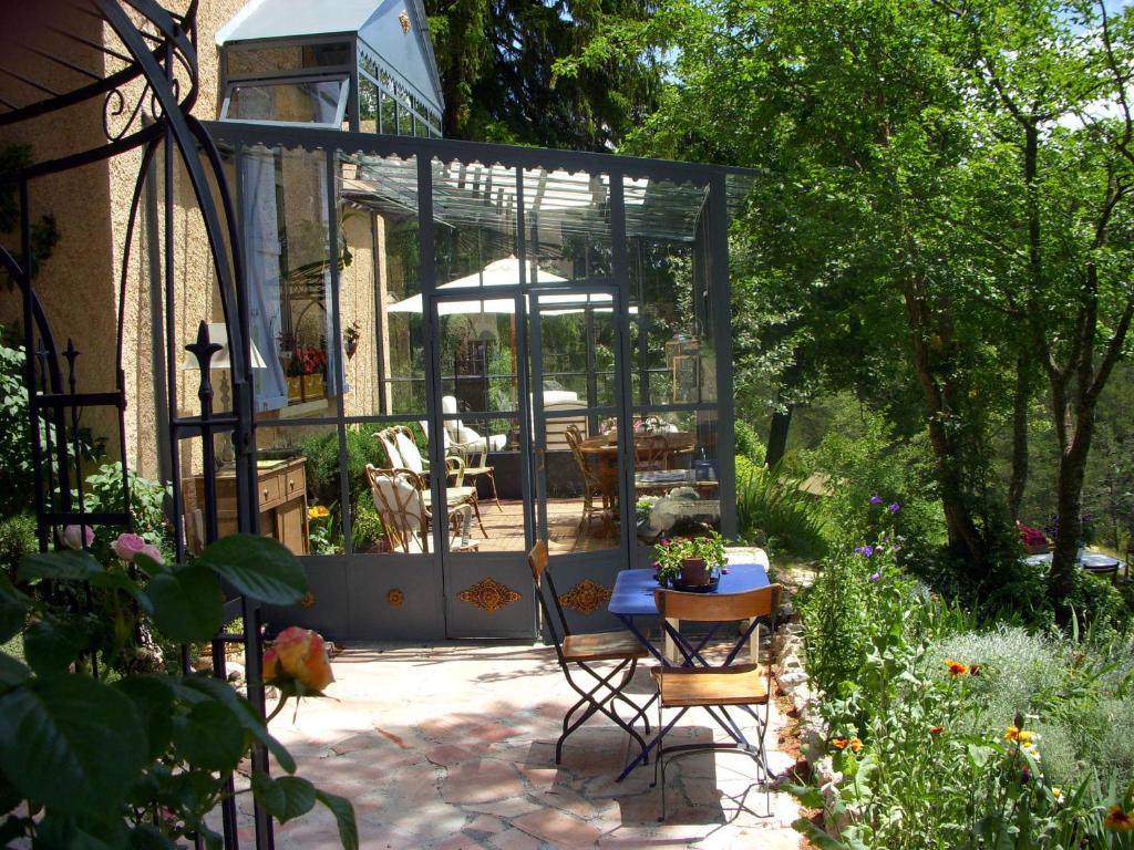 a garden with a table and a glass house at La Becassiere in Thorenc