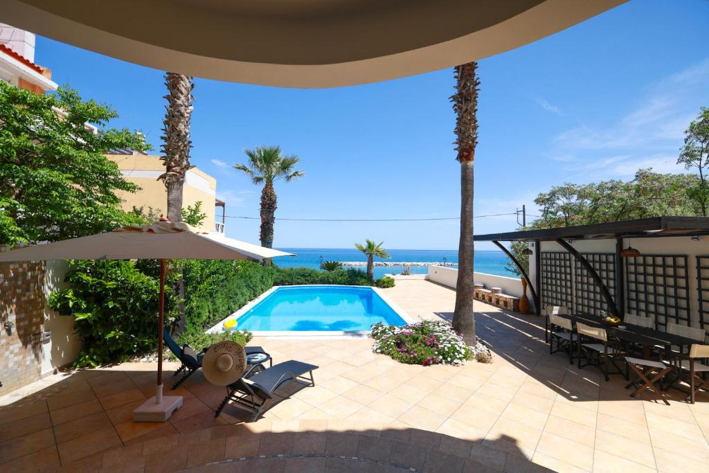 a patio with an umbrella and a swimming pool at Villa Kyma in Platána