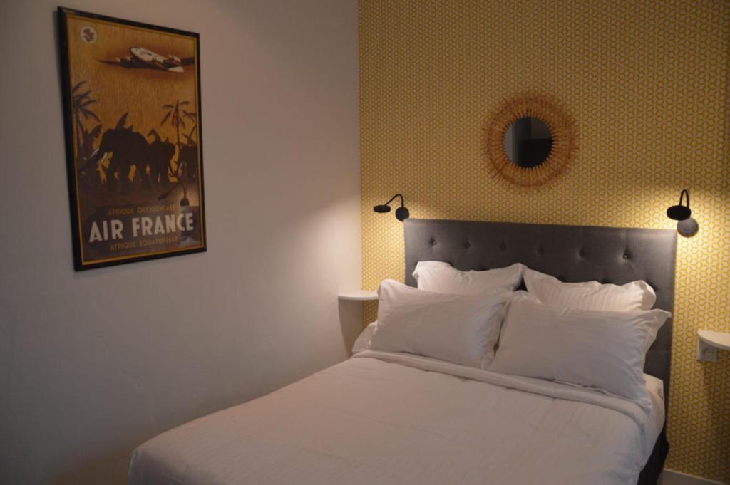a bedroom with a bed with white pillows and a picture at Hotel Castellamar in Sainte-Maxime