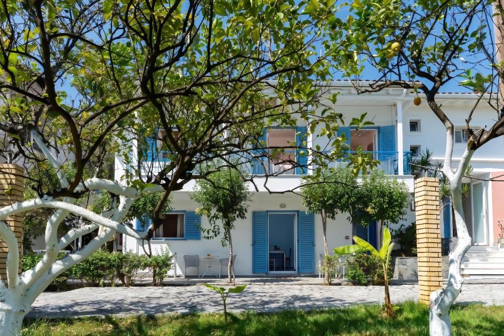 a white house with blue shutters and trees at Lemon Garden Apartments in Lygia