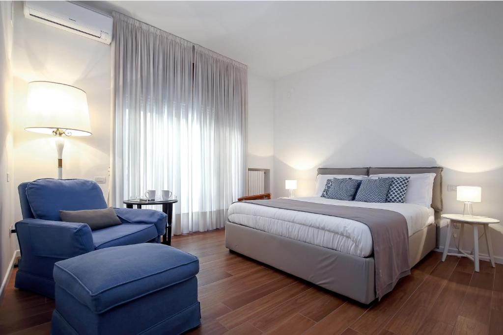 a bedroom with a bed and a blue chair at Starhost - GOLDEN APARTMENTS in Salerno