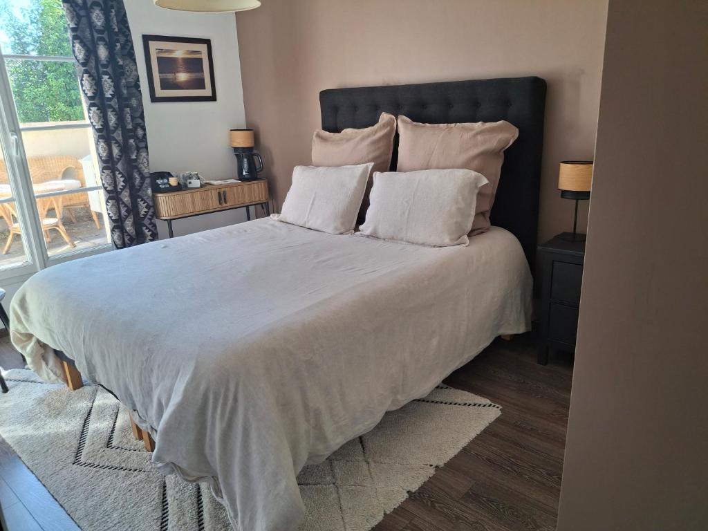 a bedroom with a large bed with white sheets and pillows at 2 chambres d'hôtes in Wissous
