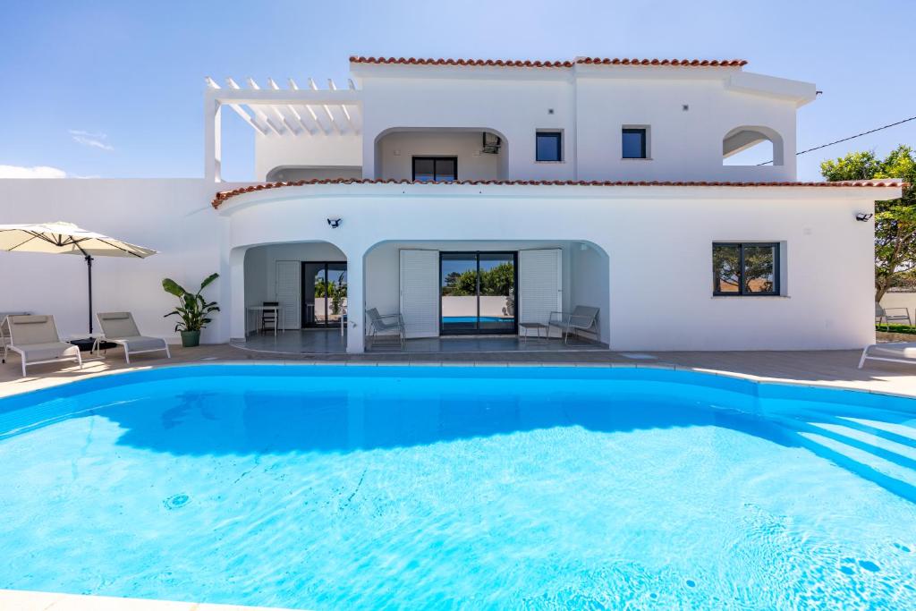 a villa with a swimming pool in front of a house at Vivenda Vilhegas in Albufeira