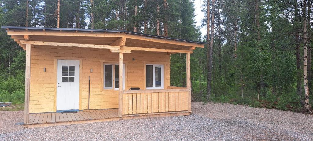 a small shed with a white door in a forest at Single room - small cabin - stuga - self check in - Gällivare Koskullskulle in Koskullskulle