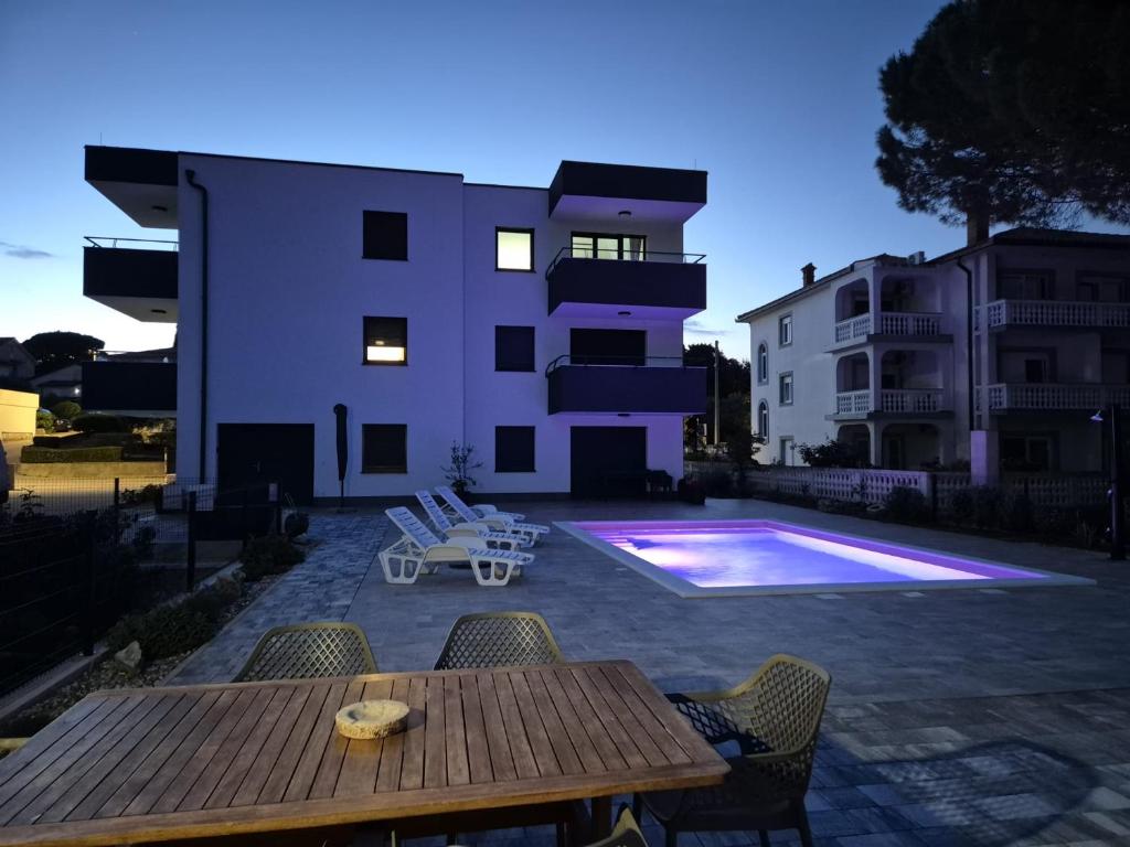 a patio with a wooden table and chairs and a building at Apartments Natalija1 -Krk in Krk