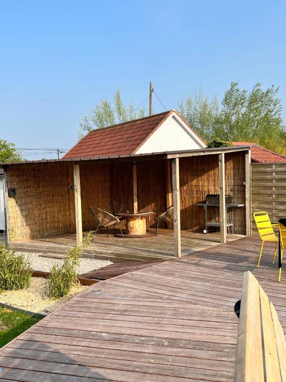 a pavilion with a table and chairs on a wooden deck at Gîte au paradis boisé in Ardres