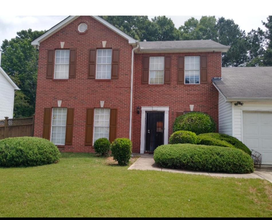 a red brick house with bushes in a yard at Nijsha Enterprise in Jonesboro