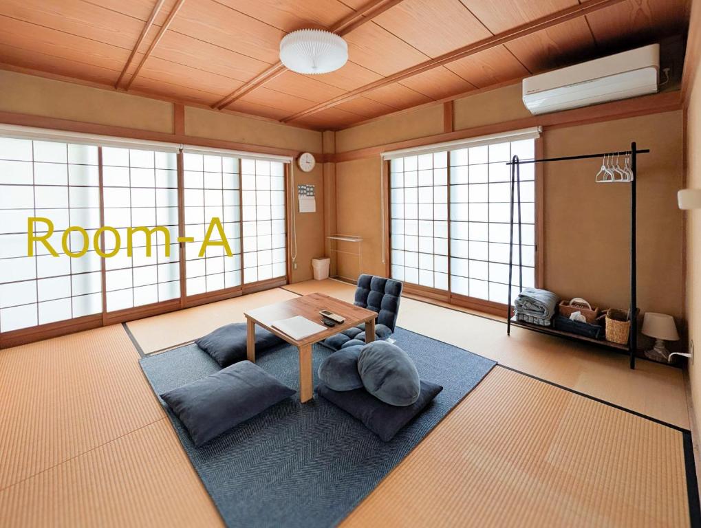 a living room with a table and chairs and windows at Denim Lodge Nest in Kurashiki