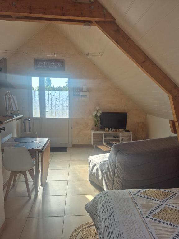 a attic room with a bed and a table and a television at Studio Cosy à la campagne, à 30 min des plages in Missillac